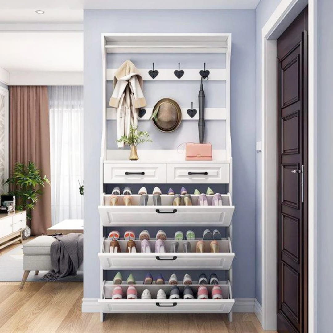 White hallway shoe rack with three open tilt-out shoe compartments displaying organised footwear, two drawers and coat hooks.