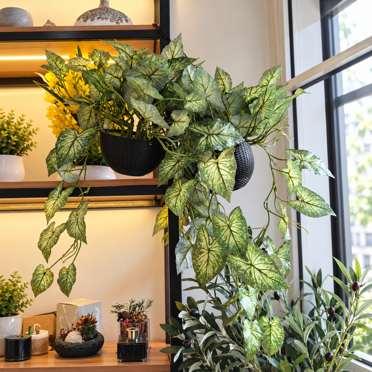 Image 1: Artificial hanging plant with green and cream leaves in a black textured pot displayed near a window.