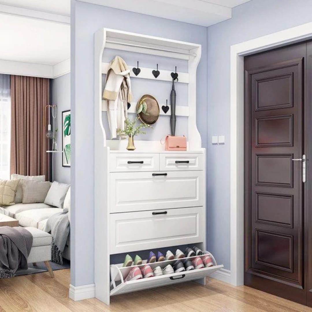 White hallway shoe cabinet with coat hooks, two drawers and three shoe compartments in a modern home entryway.