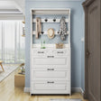 White hallway shoe and coat rack with black handles, hanging hooks and closed shoe compartments in a narrow entryway.