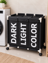 Black laundry basket with three sections labelled Dark, Light and Color, white corner connectors and four black wheels.