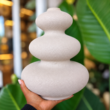 Minimalist beige stone-look ceramic vase with a three-tier design, held in hand.